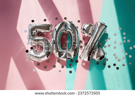 Silver numbers 50 fifty percent balloons among confetti in sunlight on pink turquoise background celebration party. Greetings and congratulation