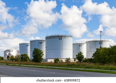 Silver Oil Tanks On The Green Grass Field. Blue Sky With Clouds.