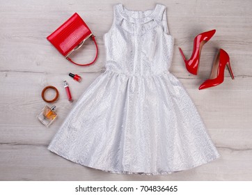 Silver Party Dress On Wooden Background. Fashion Cocktail Dress, Red Heels And Handbag Clutch, Cosmetics, Top View.