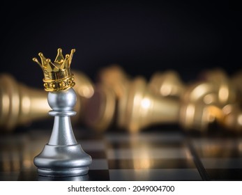 A silver pawn standing crowned in battle chess game on board with gold chess background. To fighting with teamwork to victory, business strategy concept and leader and teamwork concept for success.