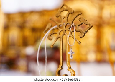 A silver pectoral cross on a string on a large gold cross of the baptismal font. Attributes and traditions of the Orthodox Church.