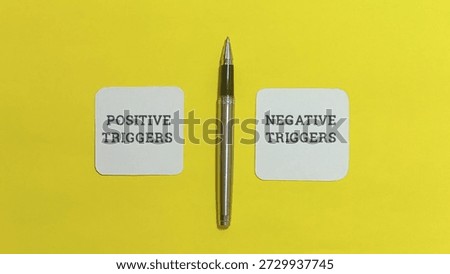 Silver pen centrally positioned between two cards labeled positive triggers and negative triggers symbolizes the crucial moment of making a conscious choice about influences affecting behavior and mood on a bright surface.