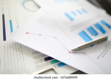 Silver pen lies on paper documents with black with red paragraphs business charts background. Risk management concept. Development of stock markets and securities strategies