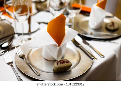 Silver Plates And Stone Nametags On A Fully Set Table With Orange Decoration