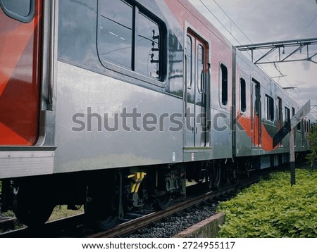 Silver and red train on tracks with green foliage nearby