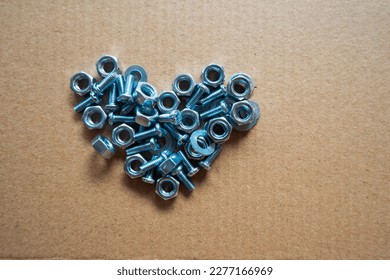 Silver screws  Bolts   nuts in heart shape   Heart lined and metal fittings brown background with empty space around heart Valentine steel heart