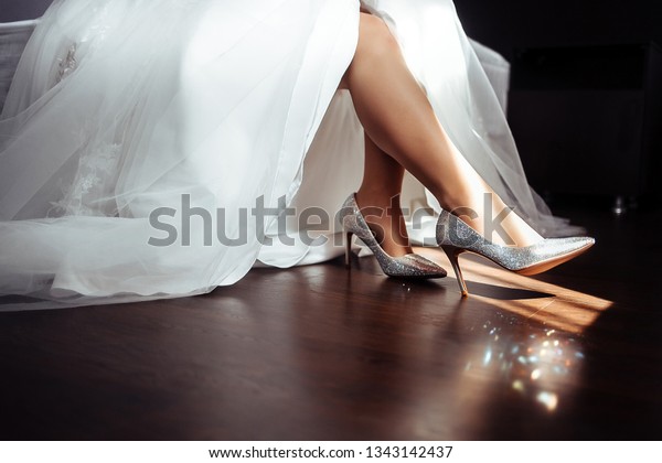 silver shoes jewel on the feet of the bride in a\
white wedding dress in the sun in the room is beautiful, preparing\
the bride for the\
morning