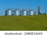 silver silos on agro manufacturing plant for processing drying cleaning and storage of agricultural products, flour, cereals and grain. Large iron barrels of grain. Granary elevator