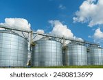 silver silos on agro manufacturing plant for processing drying cleaning and storage of agricultural products, flour, cereals and grain. Large iron barrels of grain. Granary elevator