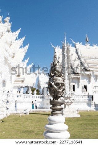 Silver skull statue with white temple and clear blue sky in background