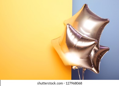 Silver Star Shaped Balloons On Yellow And Blue Background