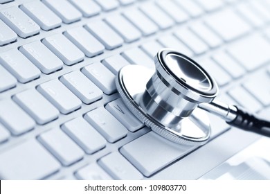Silver stethoscope lying down on an laptop, toned blue