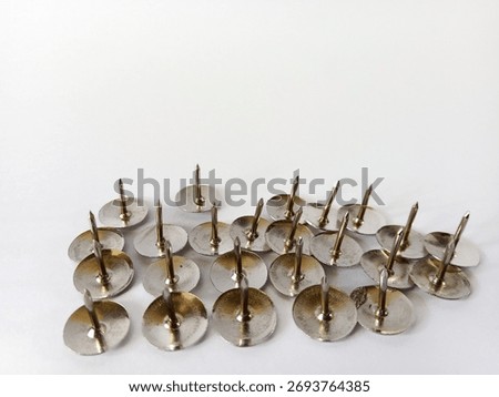 Silver thumbtacks lined up in order facing upward on clean background