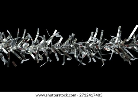 Silver tinsel string isolated on black background. Christmas ornaments.