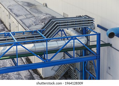 Silver Ventilation Pipe. The Side Staircase At The Industrial Building Is Painted Blue. Factory Building Outside On A Sunny Day. Horizontal Photo Outdoors.