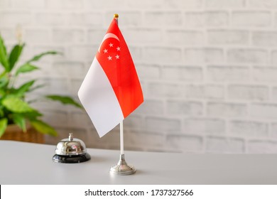 Silver Vintage Bell With National Flag Of Singapore On Reception Desk With Copy Space. Hotel Service. Travel, Tourism. Selective Focus. Asia, Concept.