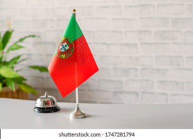 Silver vintage bell with national flag of  Portugal on reception desk with copy space. Hotel service. Travel, tourism. Selective focus. Europe, Concept.