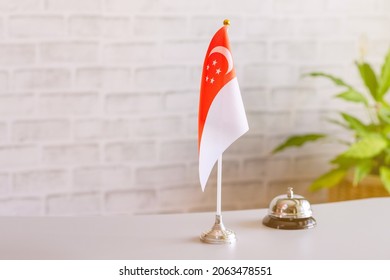 Silver Vintage Bell With National Flag Of Singapore On Reception Desk With Copy Space. Hotel Service. Travel, Tourism. Selective Focus. Asia, Concept.