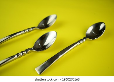 silver ware sppon on bright yellow background