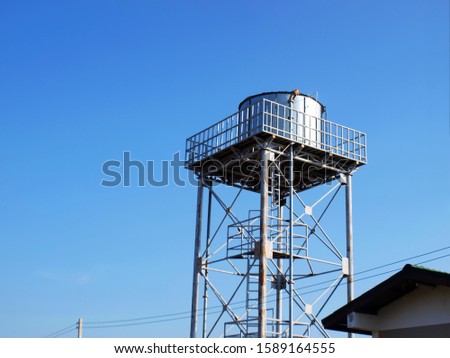Silver water tank on the tower On a clean blue sky background With copy space