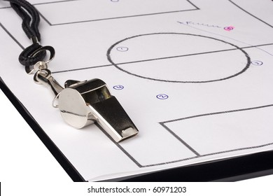 A silver whistle laying on a clipboard with the game plan on it. - Powered by Shutterstock