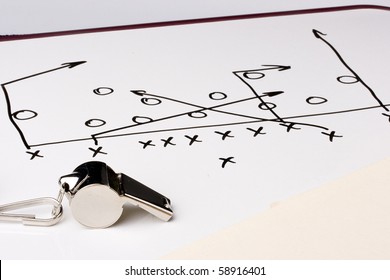 A silver whistle next to a drawing of a football play. - Powered by Shutterstock