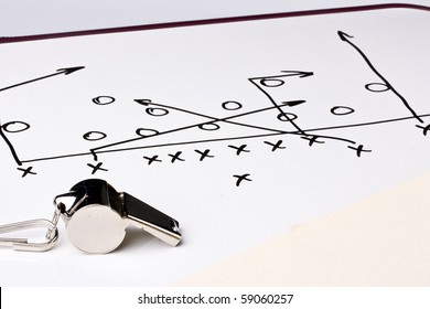 A silver whistle next to a drawing of a football play. - Powered by Shutterstock