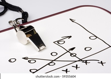 A silver whistle next to a drawing of a football play. - Powered by Shutterstock