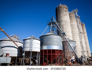 Silver and white storage silos, Agricultural industrial containers against a deep blue sky in Australia.
