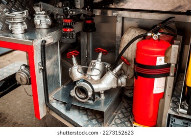 a silver-colored fire hydrant with red valves and other fire equipment lies in fire car. red extinguisher