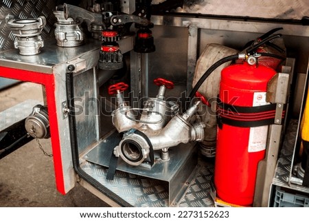 a silver-colored fire hydrant with red valves and other fire equipment lies in fire car. red extinguisher