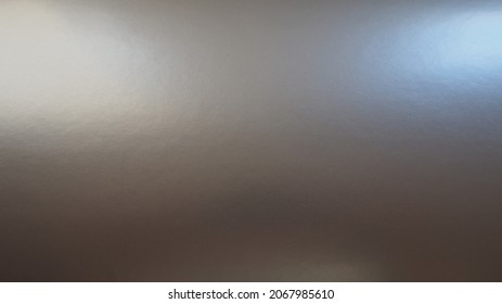 Silver-gray background with a metallic sheen, light from both sides, right and left. Abstract background with gradient. Copy space. Texture and unevenness on the surface of paper or foil. Shine foil