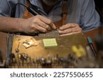 Silversmith working with tools on a jewelers bench in a traditional artisanal silversmith workshop and studio in Centro Storico in Florence, Italy