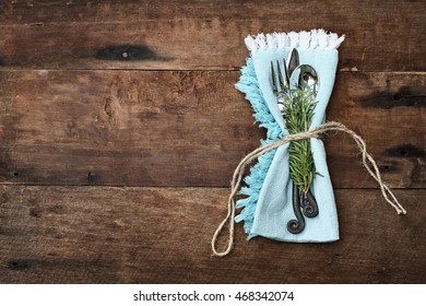 Silverware tied into a blue napkin over a rustic old flat wood table top background. Image shot from overhead. - Powered by Shutterstock