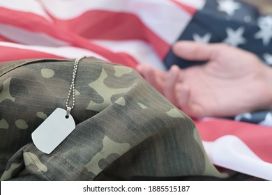 Silvery Military Beads With Dog Tag And Hand Of Dead Soldier On United States Fabric Flag And Camouflage Uniform. Killed In Action Unit. Memorial Day Concept