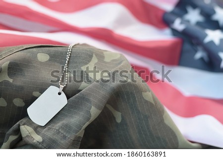 Silvery military beads with dog tag on United States fabric flag and camouflage uniform