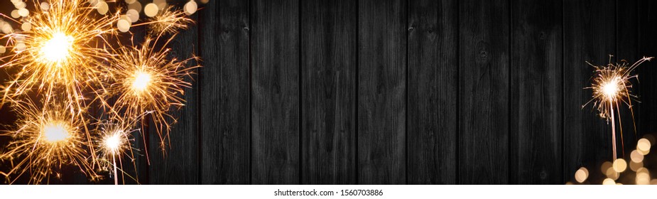 Silvester background banner panorama long- sparklers and boheh lights on rustic wooden texture, top view with space for text
