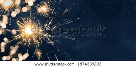Silvester party New year background banner panorama long- sparklers and bokeh lights on dark blue night sky texture, with space for text