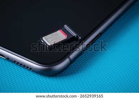 Sim card lying on a dark smartphone. Nano size SIM for modern smartphone. Selective focus.