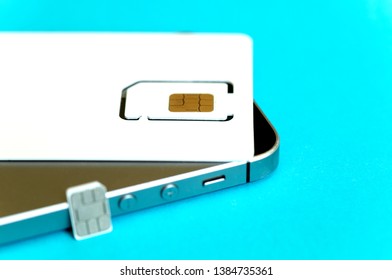 SIM Card In Package And Micro SIM Card Blurred, Mobile Phone On Blue Background, Close Up, Top View