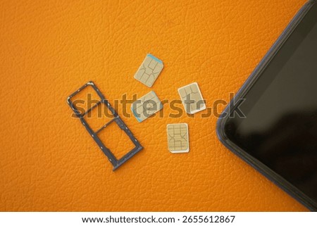 SIM card tray and multiple SIM cards on an orange surface