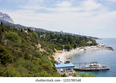 SIMEIZ, CRIMEA - JUN 9, 2018: Diving center Garbi and people on narrow rocky beach. Village is located on Black Sea coast at the foot of the mountain Cat.