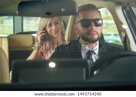 Similing driver talking with female passenger.