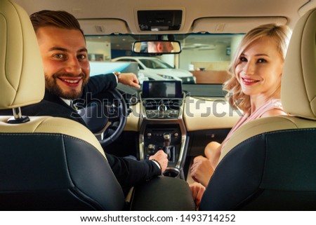 Similing driver talking with female passenger.