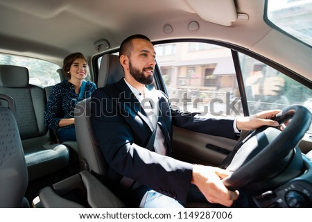 Similing taxi driver talking with female passenger. 