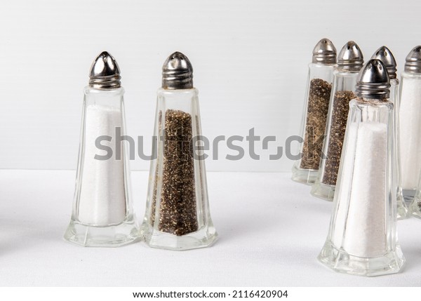 simple American restaurant or diner style salt and\
pepper shakers on a white table arranged as if they were people on\
a dance floor