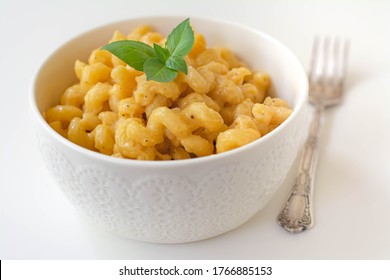 Simple American Stove-top Elbow Macaroni And Cheese Also Called Mac N Cheese Garnished With Basil On White Background