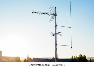 simple antenna mast with antennas to receive digital TV and radio signals, DVB-T, DVB-T2 and FM (horizontal polarization) including delayed lightning rod. In the background the peaks of roofs.