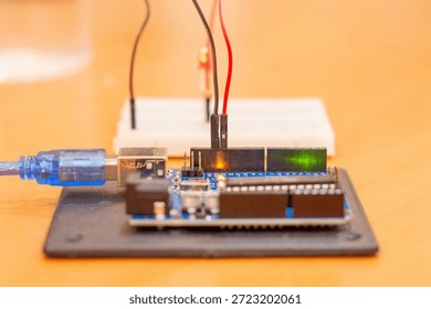 A simple Arduino microcontroller circuit featuring light-emitting diodes (LEDs) connected with resistors on a breadboard, demonstrating a basic alternating signal flasher or dual-channel output indicator for electronics beginners. Comprehensive collection of electronic components featuring an Arduino Uno R3 microcontroller board as the central processing unit for a DIY robotics project. The layout includes a variety of essential hardware for electrical engineering and prototyping, such as a white solderless breadboard, colorful male-to-male jumper wires, light-emitting diodes (LEDs) in various colors, carbon film resistors for current limiting, and integrated circuit sensors. This high-angle shot captures the essence of STEM education, hands-on learning, and the Maker Movement. Perfect for themes involving Internet of Things (IoT) development, computer science curriculum, automated system design, and hardware programming. The arrangement showcases the precision of modern circuitry and the accessibility of open-source hardware for students, engineers, and hobbyists building smart home devices or autonomous robot prototypes.