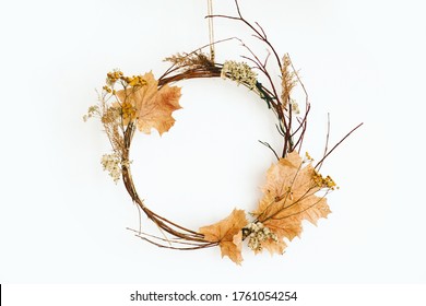 Simple Autumn Wreath Hanging On White Wall. Modern Rustic Autumn Wreath Made Of Branches, Twig, Fall Leaves, Dried Herbs And Flowers. Seasonal Decor At Home